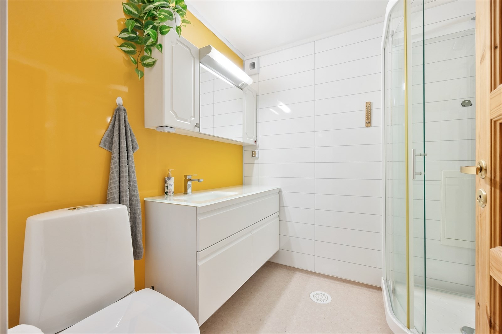 Badet er utstyrt med dusjkabinett, servant i innredning og klosett Galleribilde