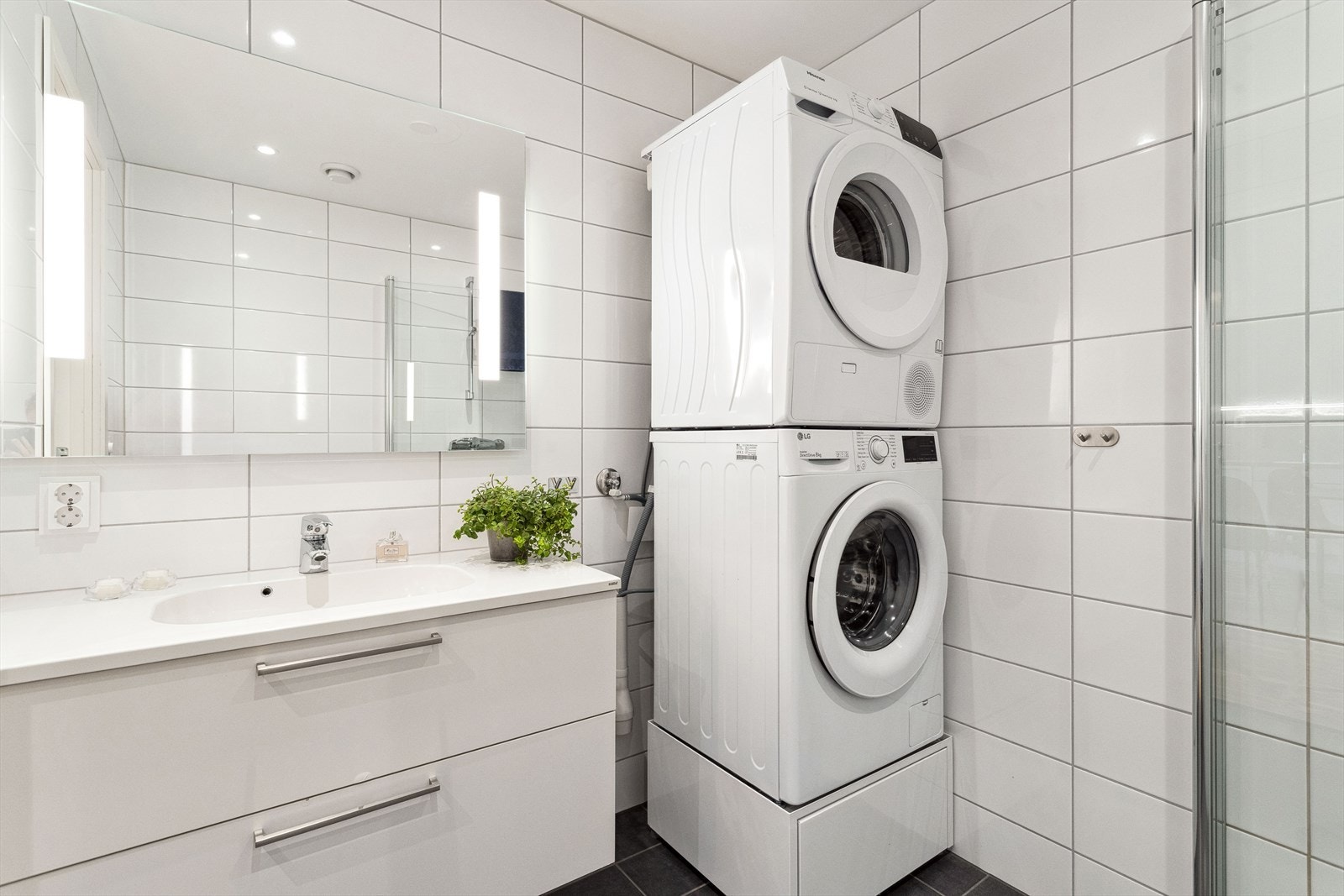 Badet har dusjvegger av glass, vegghengt toalett, innredning med servant samt opplegg for vaskemaskin. Galleribilde