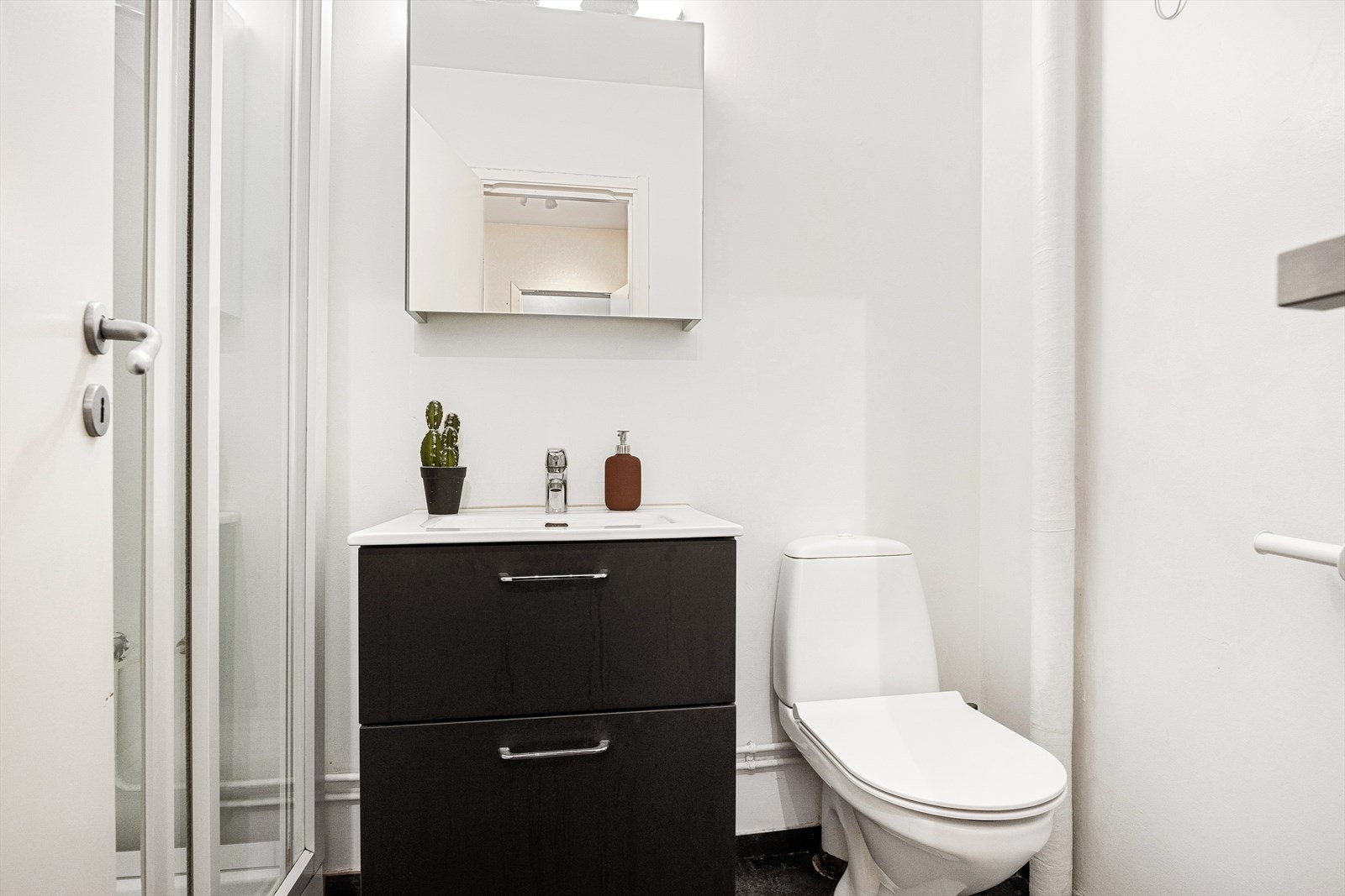 Flott baderom med flislagt gulv, hvor det er lagt vinylgulv oppå. Det er plass til en toppmatet vaskemaskin på badet. Galleribilde