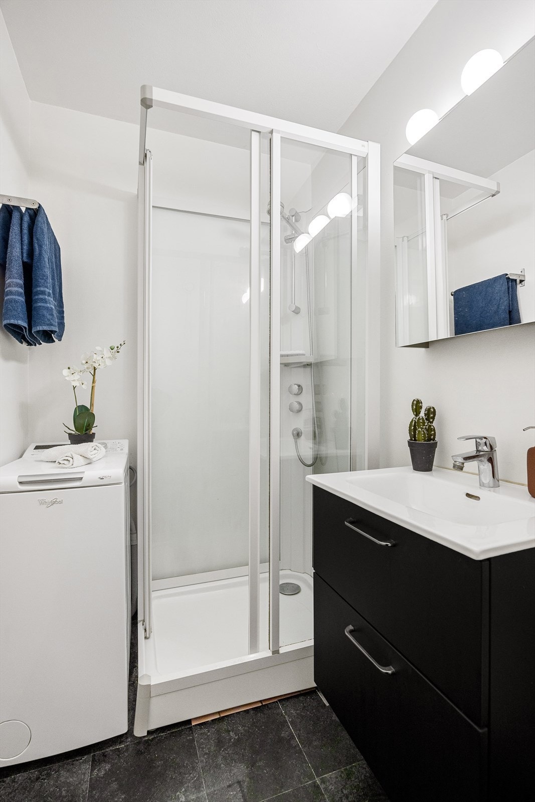Badet har et servantskap med glatte, folierte fronter og en heldekkende servant. Over servantene er det et speilskap med lysarmatur på veggen. Galleribilde
