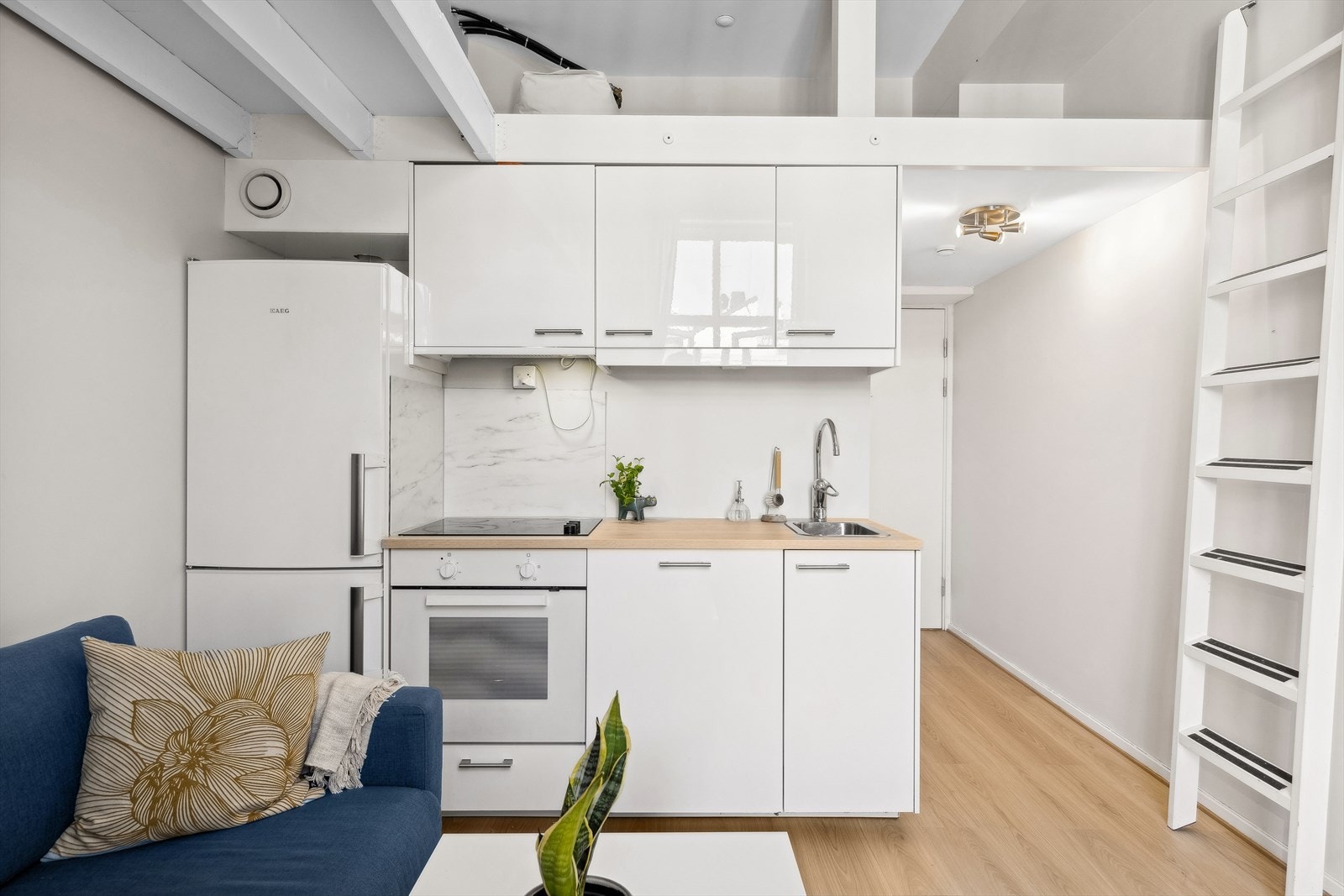 Åpen kjøkkenløsning. Kjøkkenet har en lys innredning fra 2015 fra IKEA med glatte fronter. Plater på vegg over induksjonstopp. Laminat benkeplate med nedfelt kum i rustfritt stål. Ventilator. Galleribilde