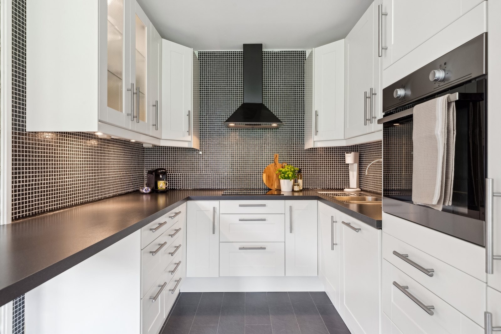 Kjøkkenet er ca 12 m² og har innredning som består av over- og underskap med folierte fronter og skrog. Mekanisk avtrekk over stekesonen. Galleribilde