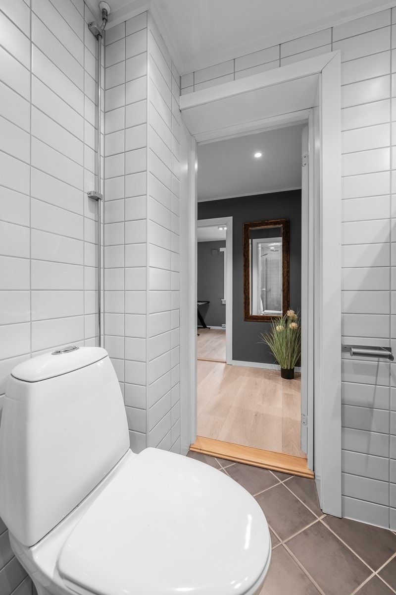 Det er tidløst valg av fliser både på gulv og vegger. Varmekabler i gulv. Senket tak med downlights. Det er toalett, servant med skap, overskap med speifronter, dusjhjørne med svingbare glassdører. Galleribilde