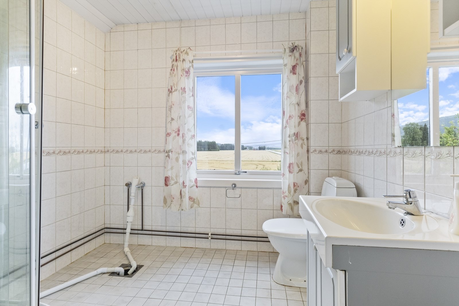 Flislagt bad beliggende i 2. etasje med gulvmontert toalett, servant i innredning, dushjørne med dusjkabinett, opplegg for vaskemaskin og mekanisk avtrekk. Badet har sørvendt vindu og behandlet panel i himling. Galleribilde