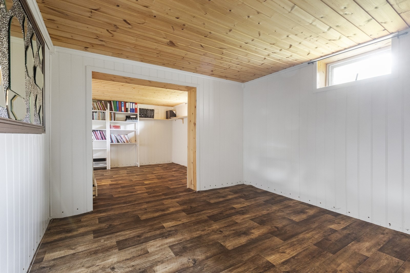 Kjellerrommene på nordlig side av boligen er i delvis åpen løsning, og har belegg på gulv, panelplater på vegg og trepanel i himling.. Galleribilde