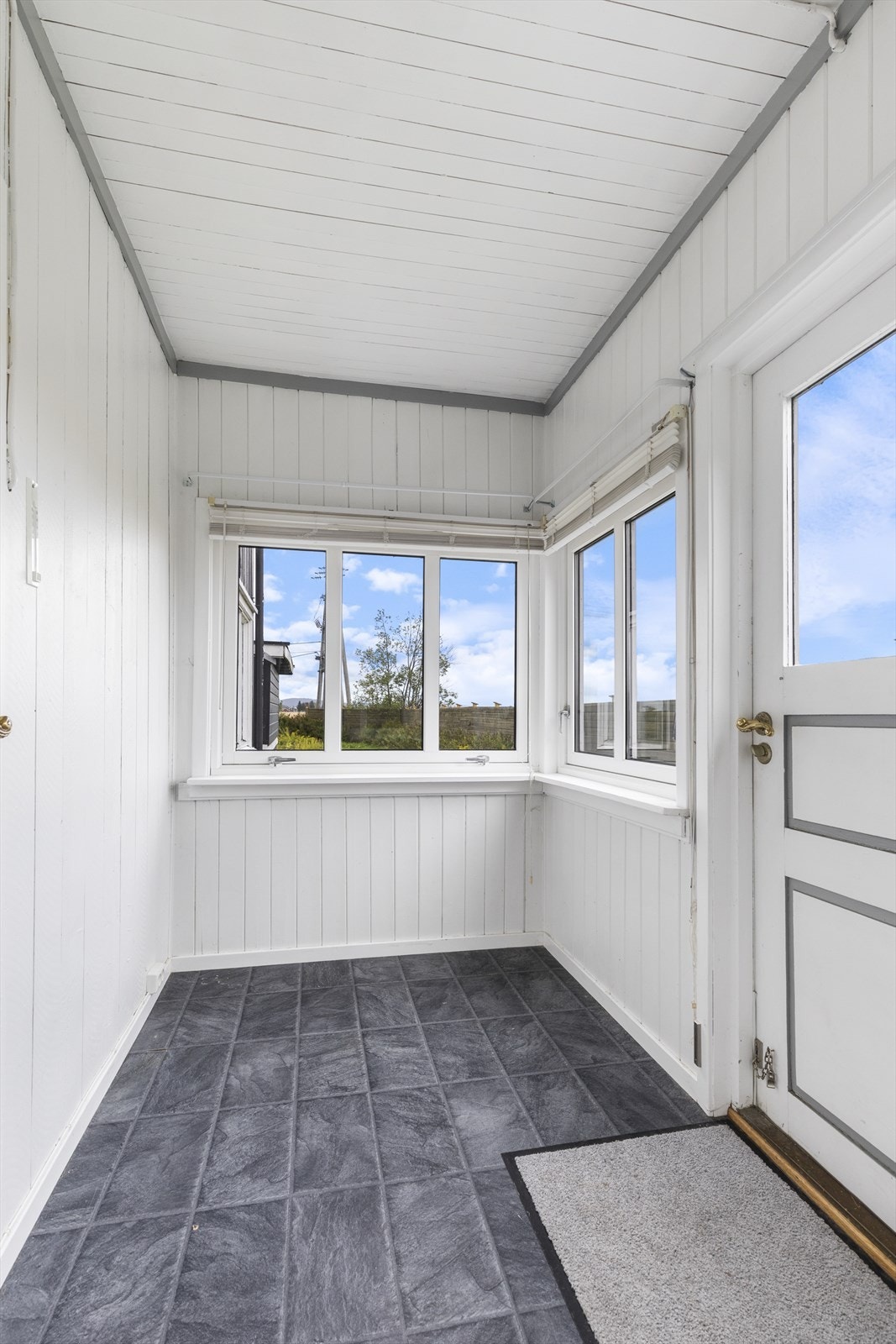 Innglasset terrasse med vinduer på tre sider og utgang med trapp til hagen mot vest og sør. Galleribilde