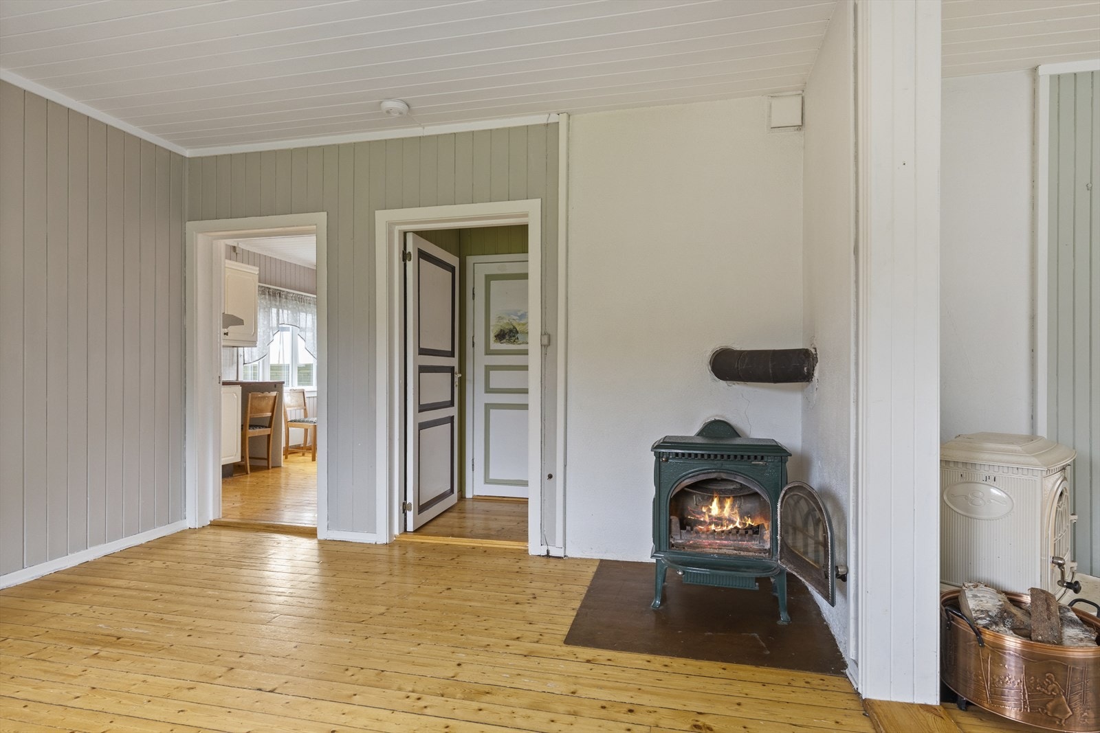 Spisestuen med tilkomst til kjøkkenet og trappegangen, har montert vedovn på hver sin side av pipeløpet. Galleribilde