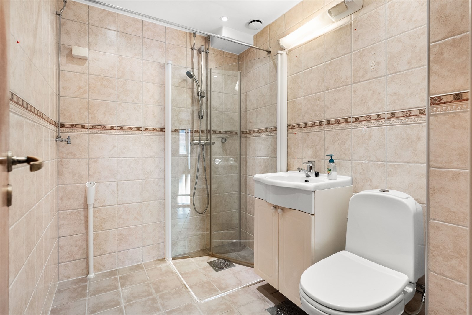 Flislagt bad med varme i gulv. Innsvingbare dusjdører og fast klosett. Opplegg for vaskemaskin Galleribilde