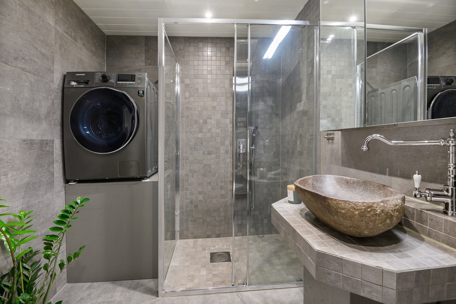 Dusjdører i herdet glass, vegghengt WC og plassbygd baderomsinnredning i samme flis som resten av veggene. Galleribilde