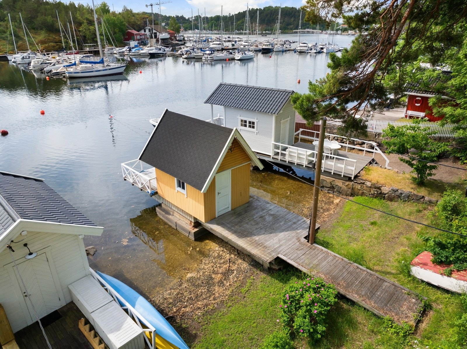 Båtbøye og båthus med landgang og uteplasser på begge sider. Galleribilde