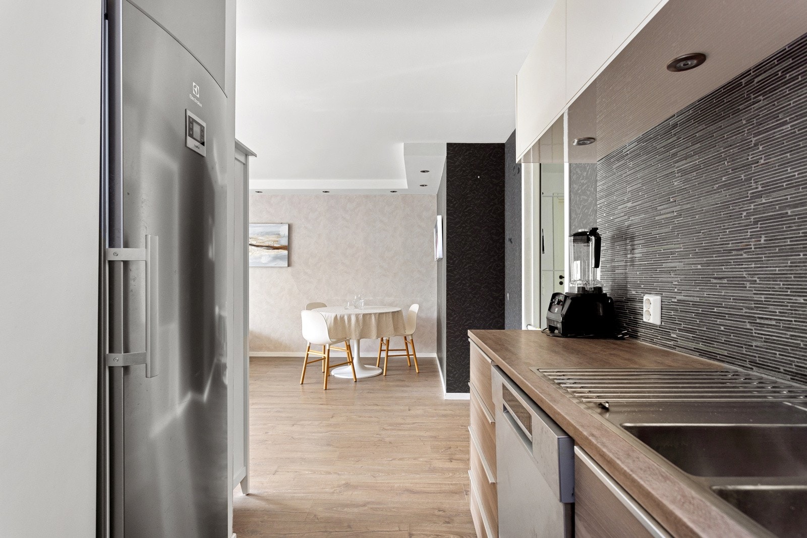 Åpen kjøkkenløsning mot stue. Kjøkkeninnredning med slette fronter fra 2013. Benkeplate av laminat. Nedfelt oppvaskkum i rustfritt stål med ettgreps armatur. Fliser og stikkontakter på vegg samt benkeskapsbelysning over kjøkkenbenk. Galleribilde
