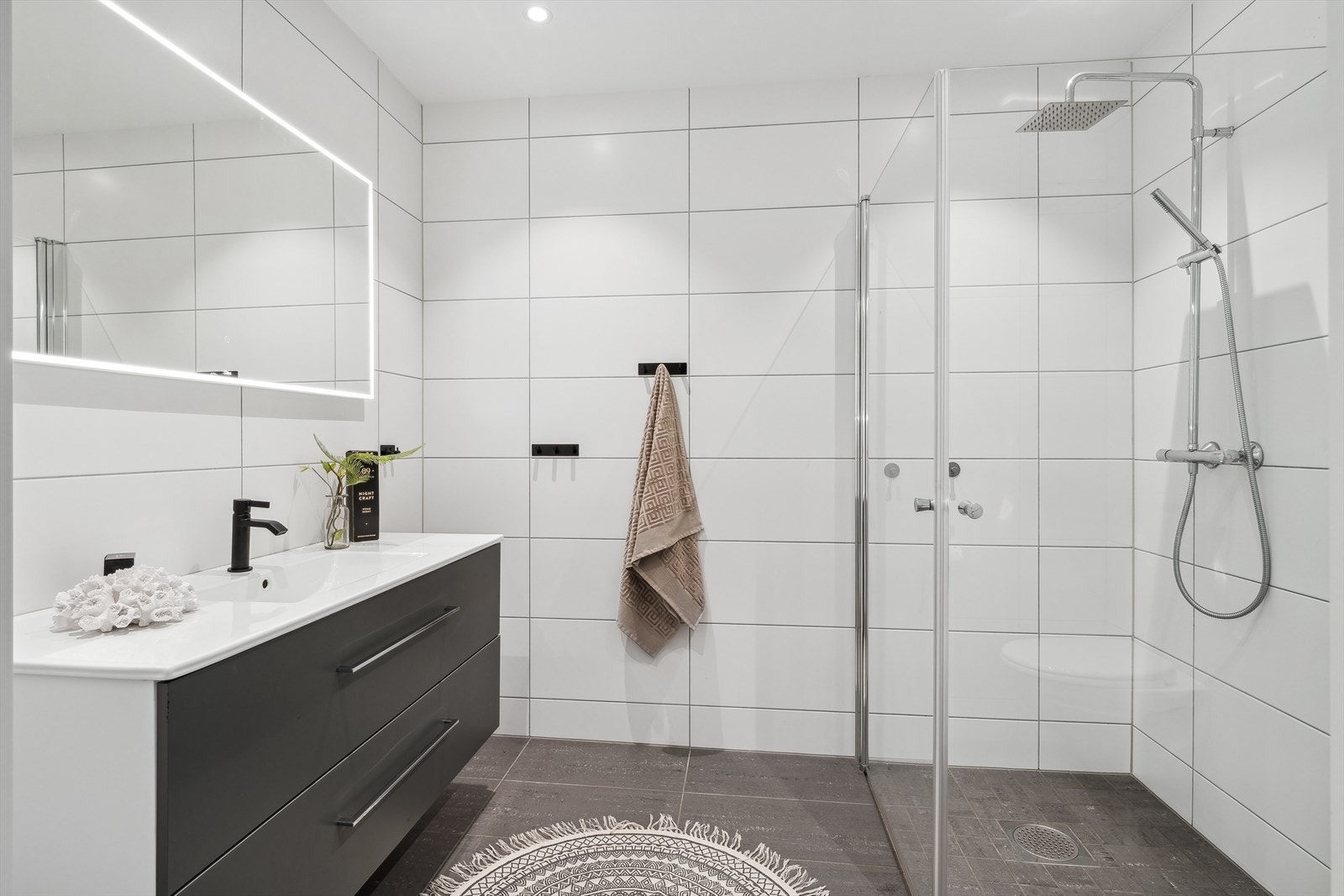 Badet ligger i andre etasje og er holdt i tidløse farger med hvite veggfliser og mørke gulvfliser over gulvvarme. Galleribilde