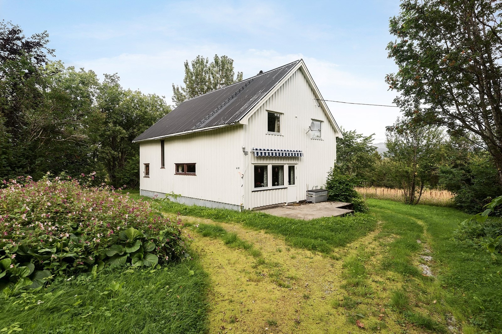 boligen ligger skjermet til med ulik beplantning rundt hagen. Galleribilde