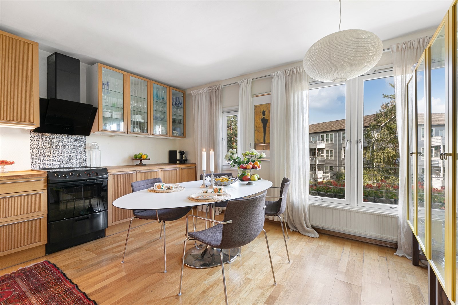 En innbydende kjøkken med åpen spiseplass, og store vinduer som slipper naturlig lys mot kjøkkenet. Galleribilde