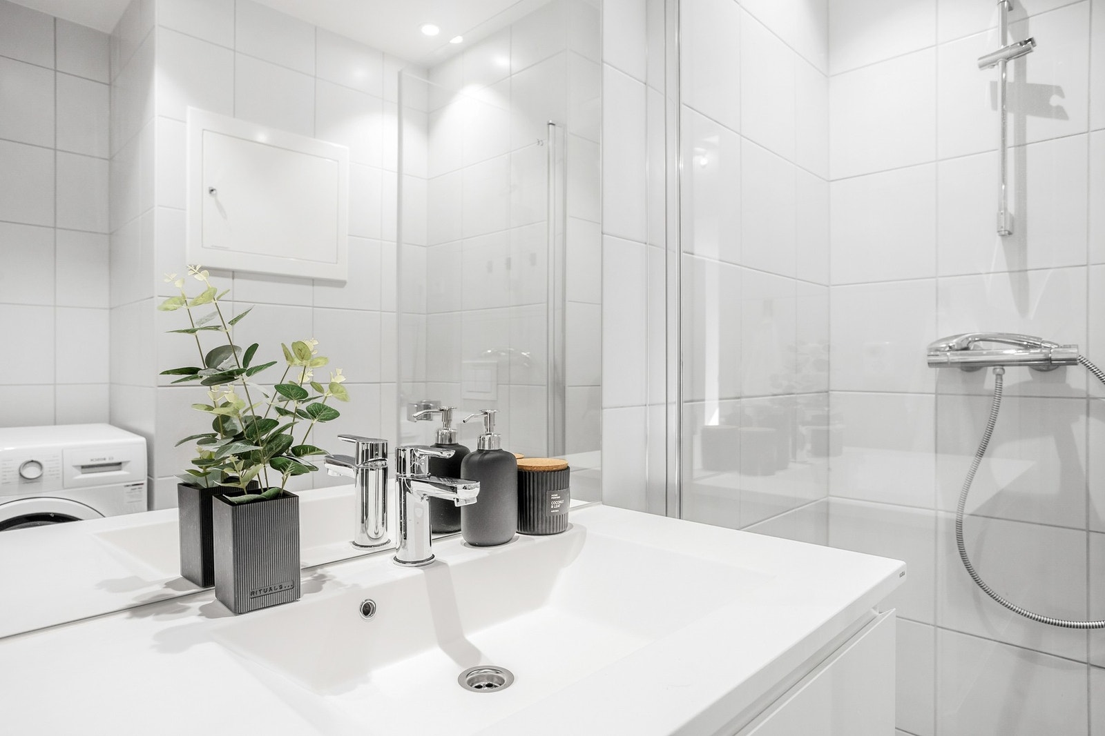 Innredet med servantinnredning, dusjdører, opplegg for vaskemaskin og wc. Galleribilde