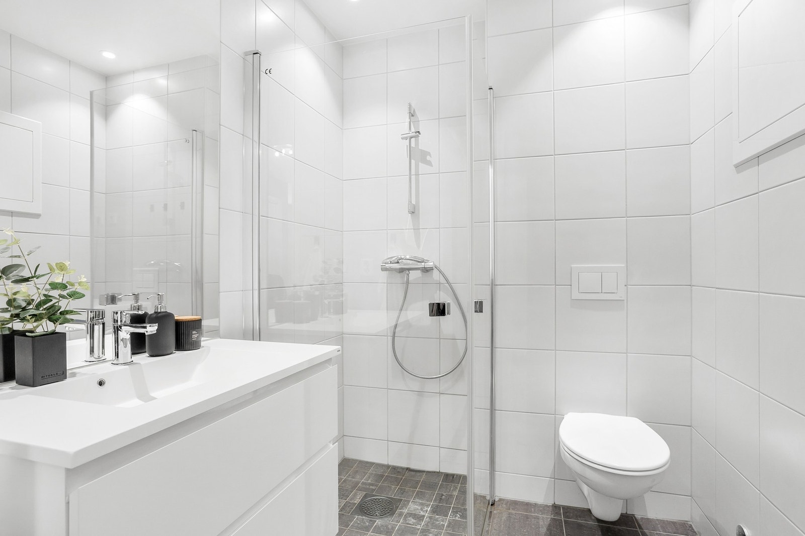 Badet har fliser på gulv med varme. Flislagte vegger og malte slette plater med downlights i innvendig tak. Galleribilde