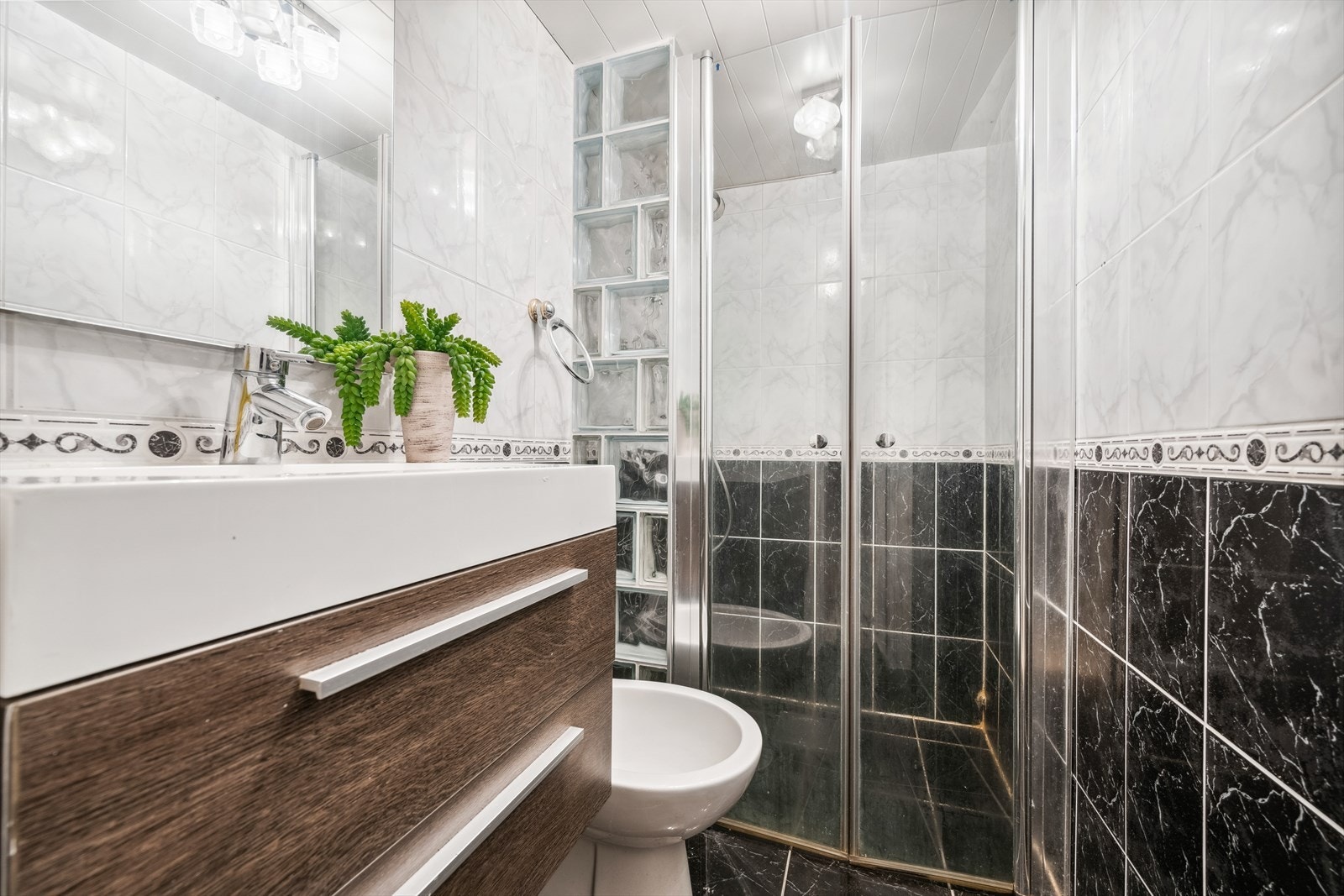 Flislagt bad beliggende i kjeller, utstyrt med toalett, dusj og innredning med servant. Galleribilde