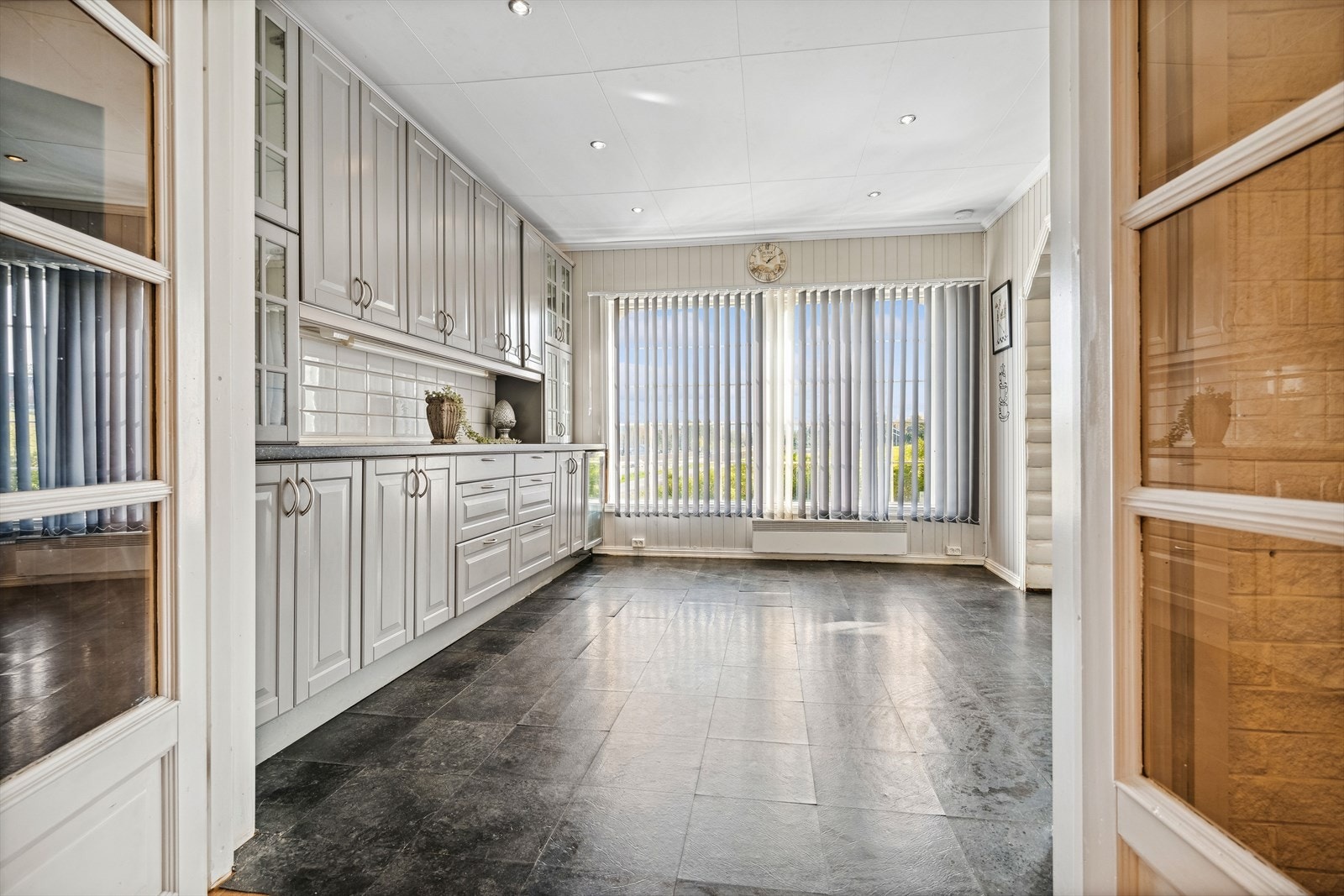 Kjøkkenskap strekker seg helt opp til taket og fliser på vegg bak benk er både pent og praktisk. Galleribilde