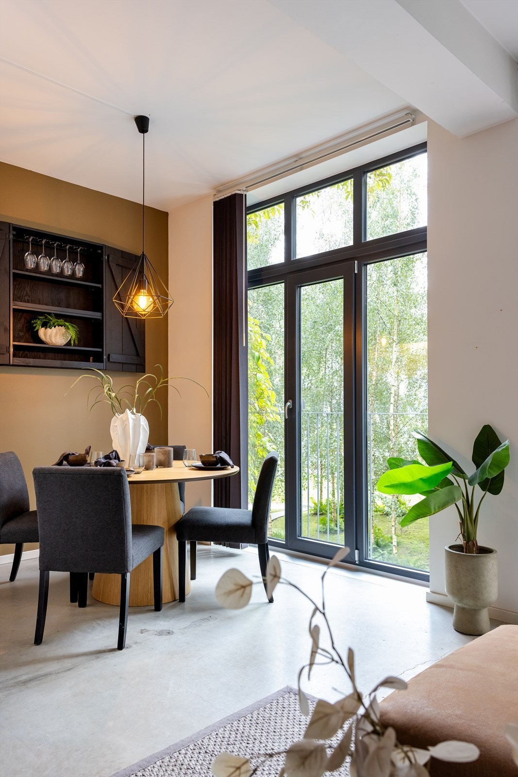 De store vinduene fra gulv til tak slipper inn rikelig med naturlig lys og gir en fantastisk utsikt mot den frodige bakgården, noe som skaper en lys og innbydende atmosfære i stuen. Galleribilde