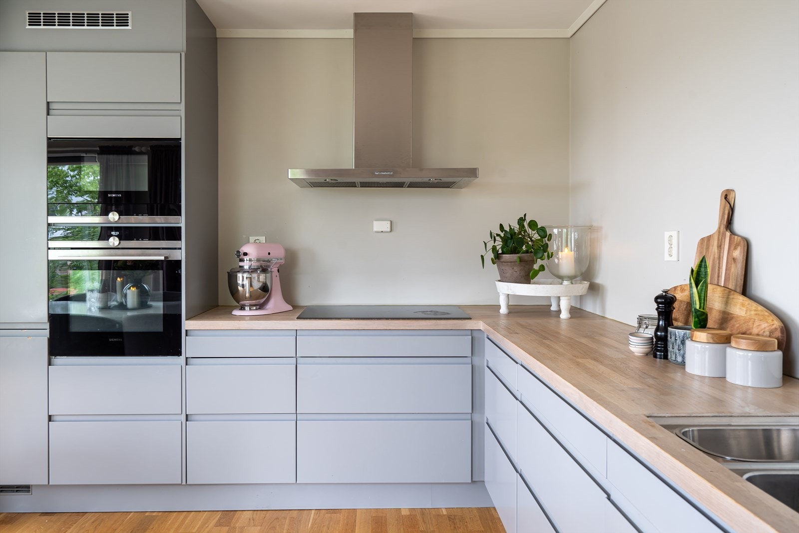 Tidsriktig kjøkken med grå fronter og benkeplate i hvitpigmentert heltre. Galleribilde