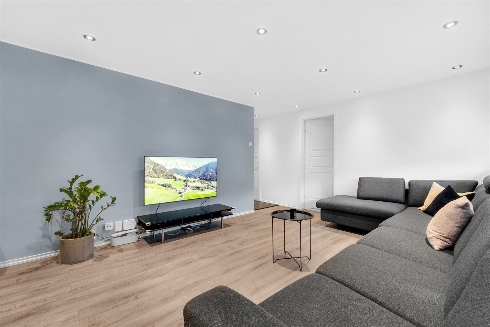 Romslig, lys og luftig stue med laminat på gulv, malte slette vegger og malt tak med downlights. Galleribilde