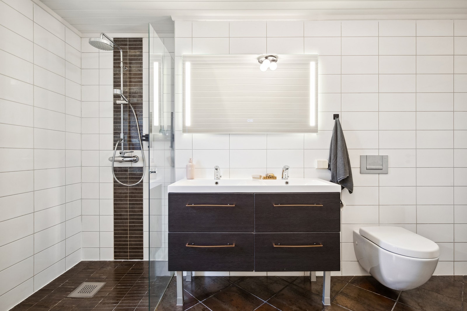 Lyst og moderne bad med dusjnisje, vegghengt toalett og stilrent servantskap. Galleribilde