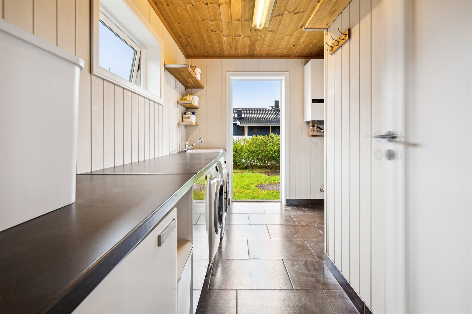 Praktisk og romslig vaskerom med direkte utgang til hagen, ideelt for en funksjonell og effektiv hverdag. Galleribilde
