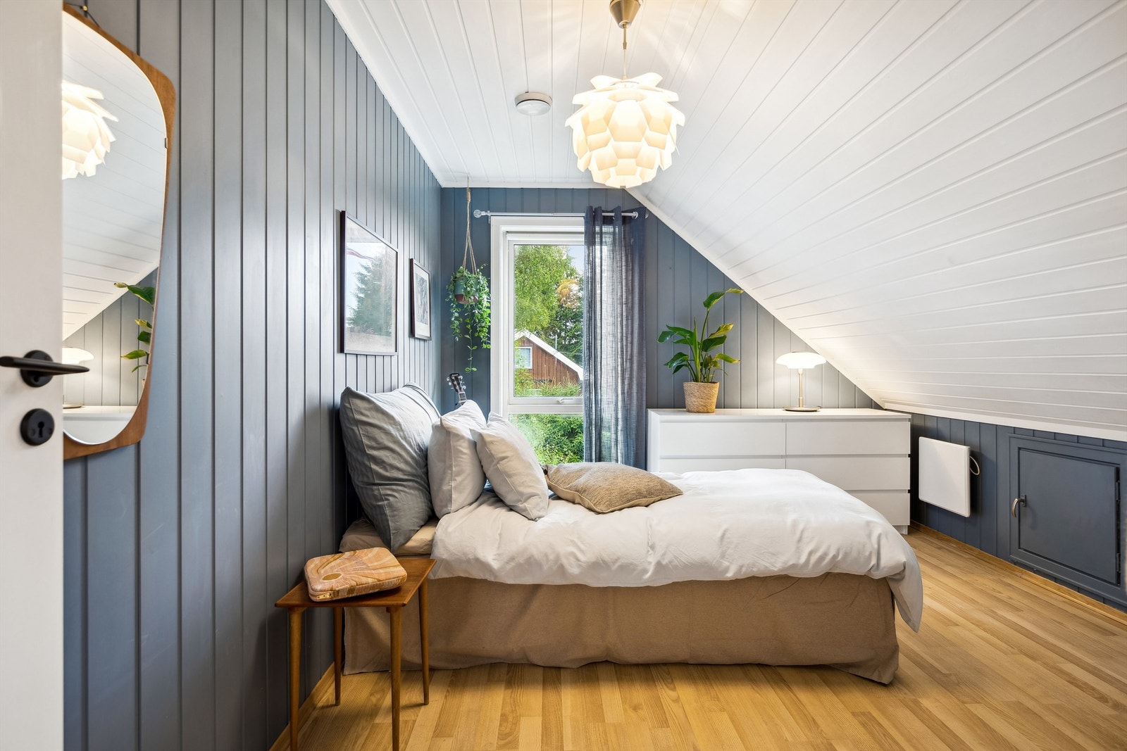 Lyst og innbydende soverom med stort vindu som gir naturlig lys og utsikt til hagen. Galleribilde