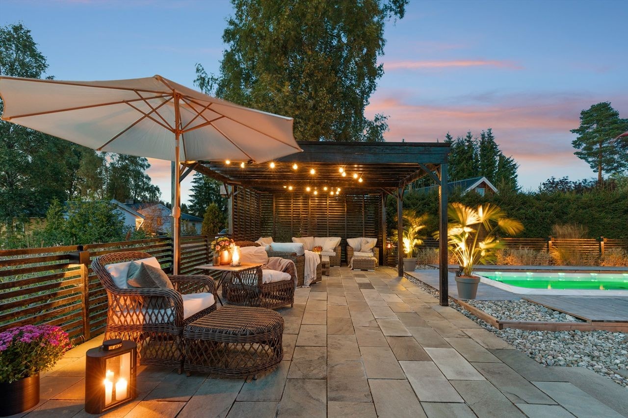 Romslig og stilfull uteplass med pergola, belysning og basseng. Perfekt for avslapning og sosiale sammenkomster Galleribilde