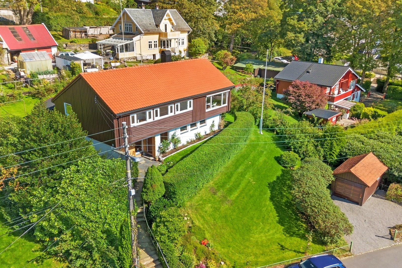 Stor tomt opparbeidet med grøntarealer, murer/bed, hekk, flaggstang, uthus og biloppstillingsplass med plass til flere biler, hvorav en i garasje. Galleribilde