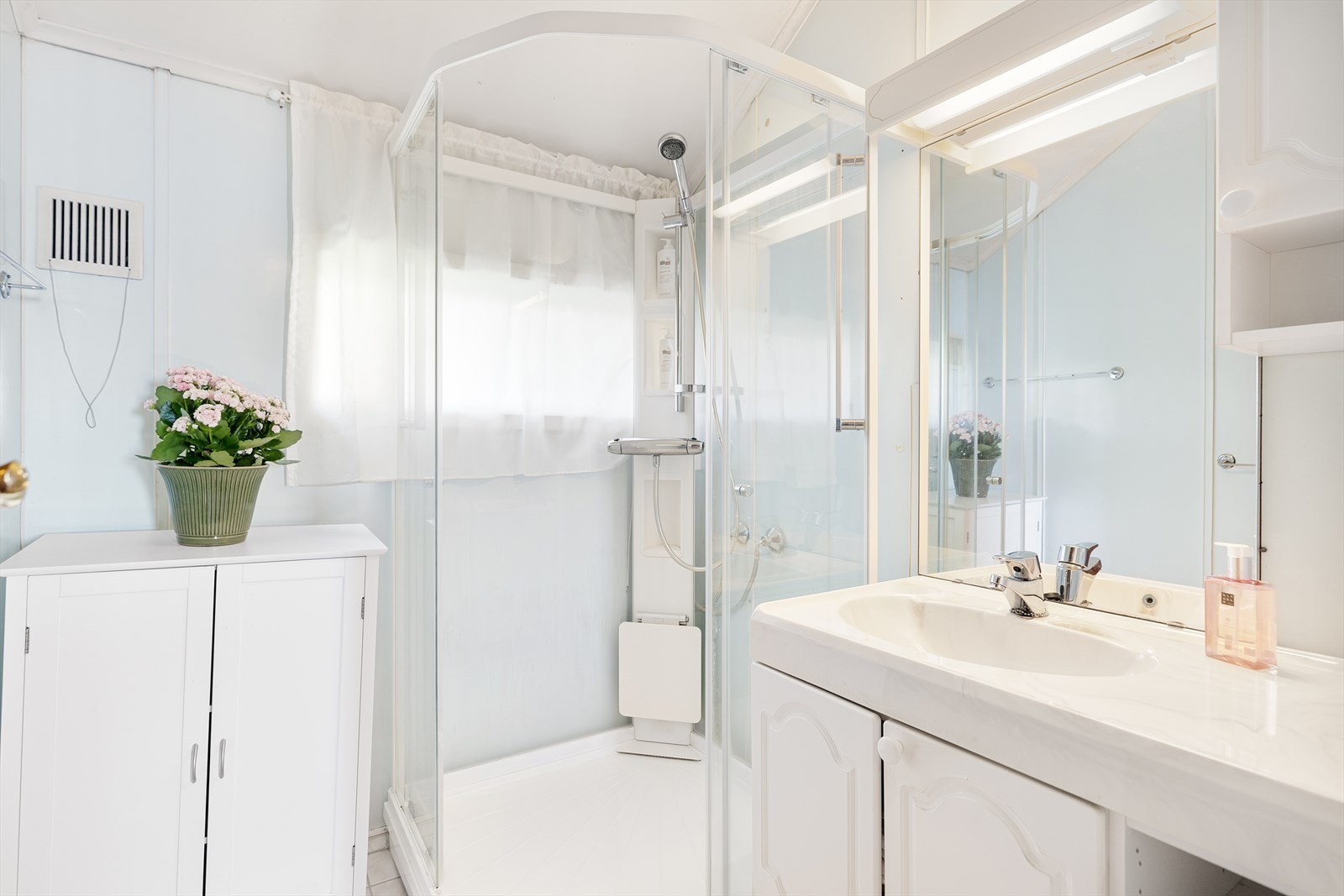 Bad med keramiske fliser på gulv, baderomsplater på vegger og malt platekledning i himling. Inneholder: Servant med møblement/speil/ belysning, dusjkabinett. Avtrekksventil i vegg/himling. Varmekabler i gulv. Galleribilde