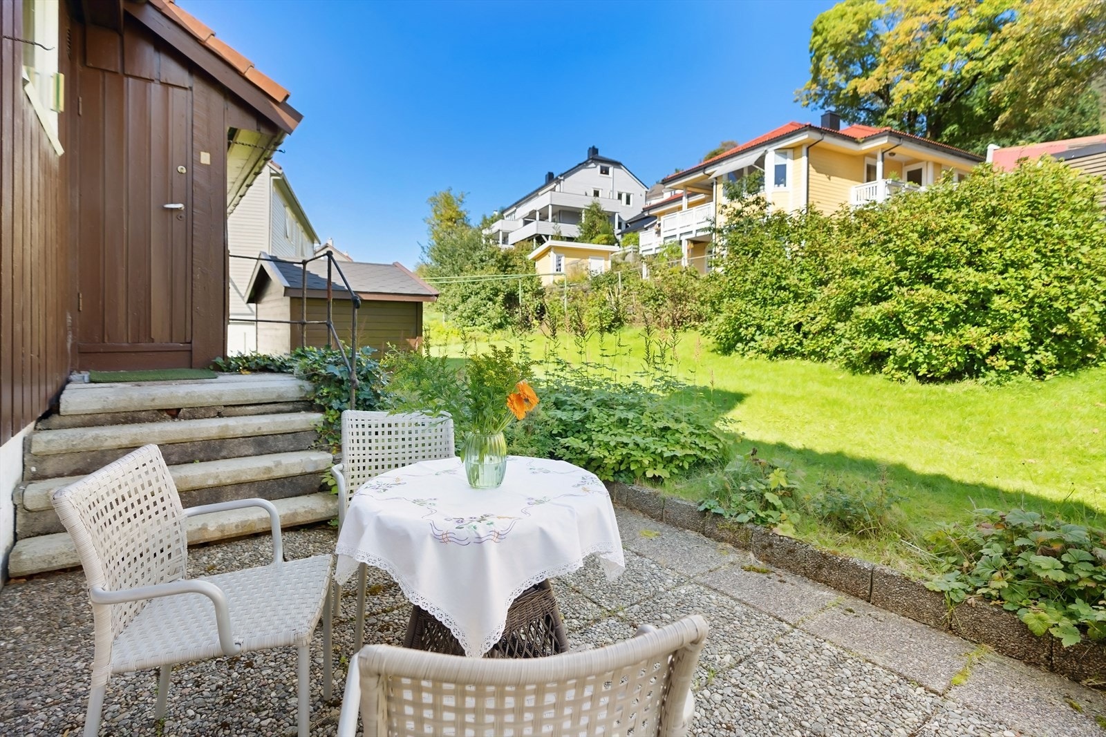 Utgang fra kjøkkenside, vaskerom/bod til bakhage og koselig sittegruppe med fin morgen-/formiddagssol. Praktisk tørkestativ gjør jobben både effektiv og miljøvennlig. Galleribilde