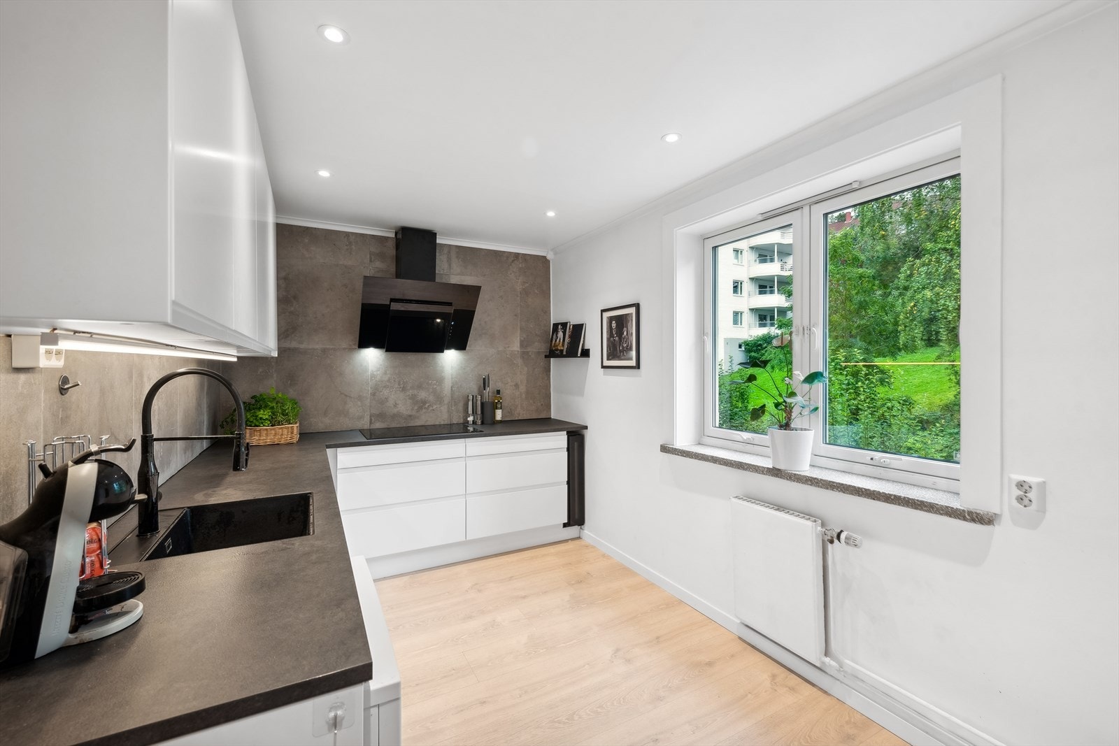 Kjøkkenet er innredet med folierte fronter, laminat benkeplate og fliser på vegg over benk Galleribilde