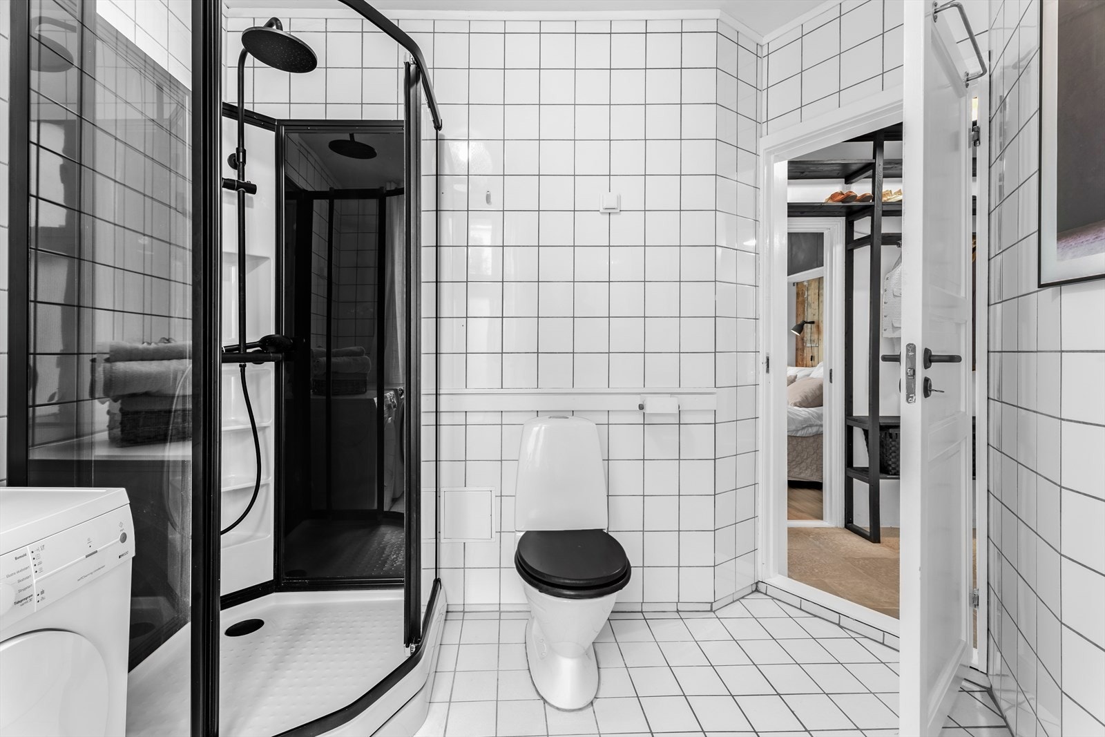 Badet er utstyrt med et lukket dusjkabinett, en servantinnredning, et gulvmontert toalett og opplegg til vaskemaskin og tørketrommel. Galleribilde