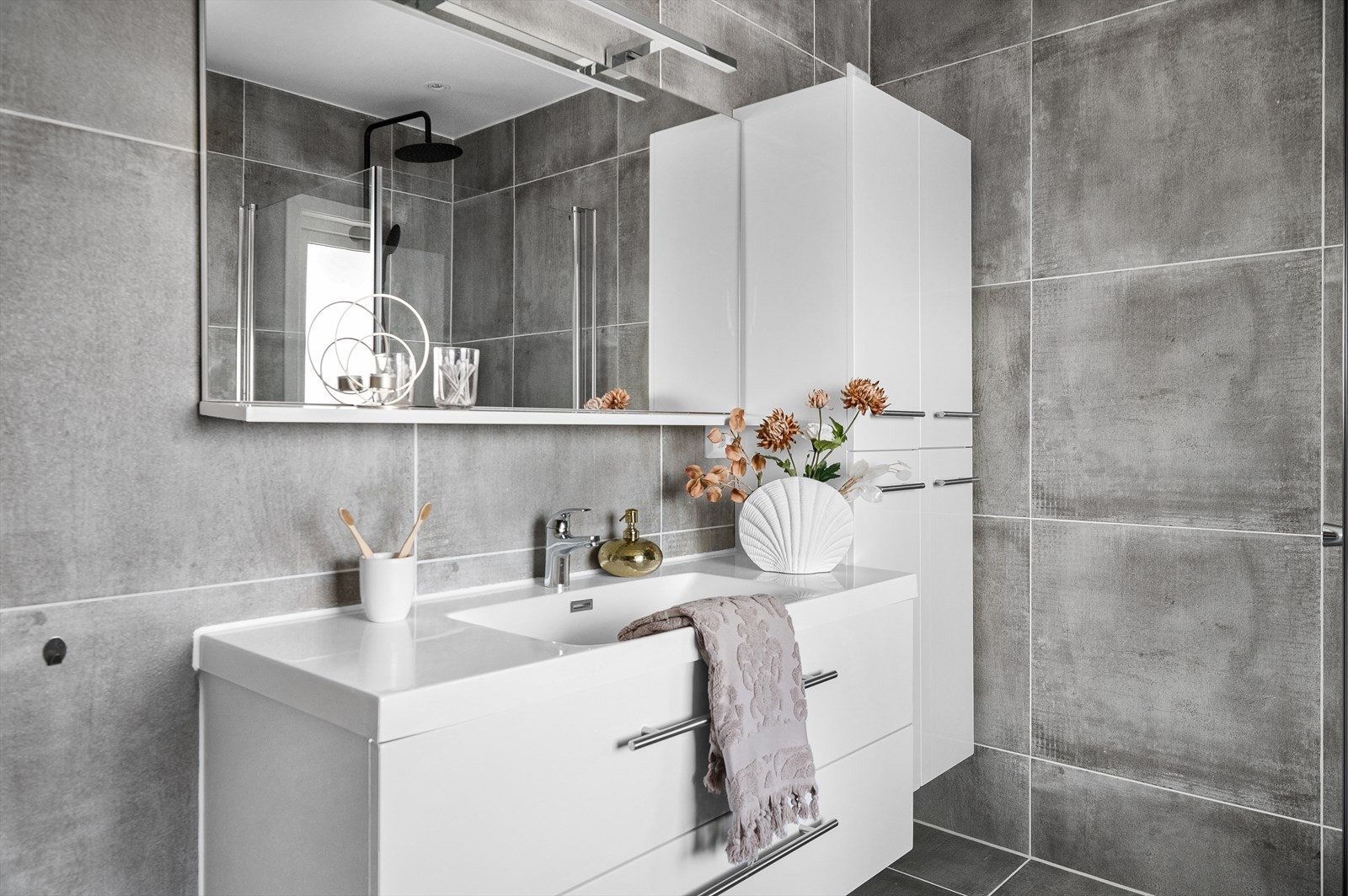 Det inneholder et vegghengt toalett, speil med integrert belysning for en sofistikert touch, samt en romslig servant med underskuffer og et pent sideskap for oppbevaring. Galleribilde