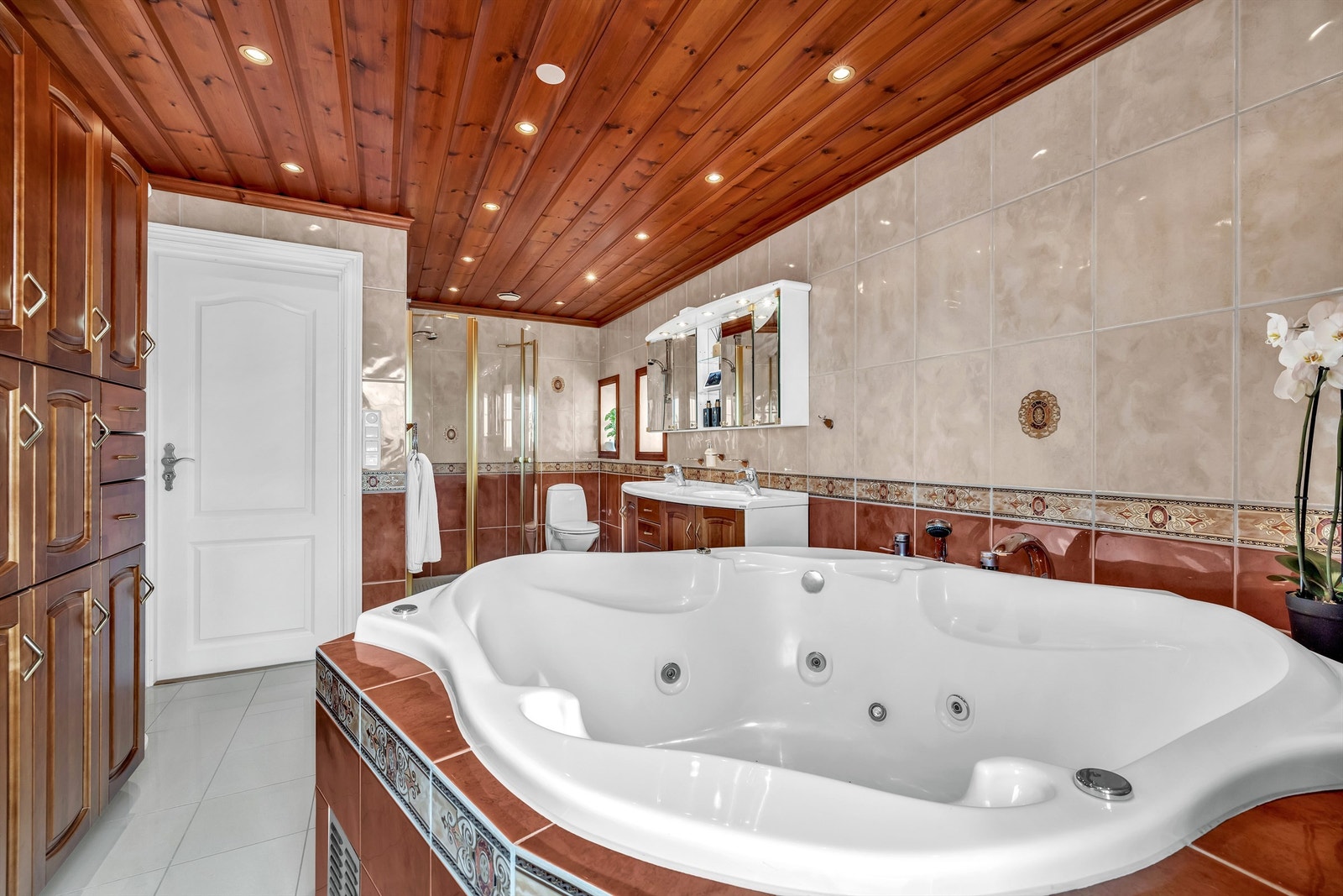 Innfliset badekar med jetstråler og boblefunksjon. Dusjen har ekstra bredde (110 cm) med glassfronter. Innredning med dobbelvask. Frittstående toalett. Galleribilde