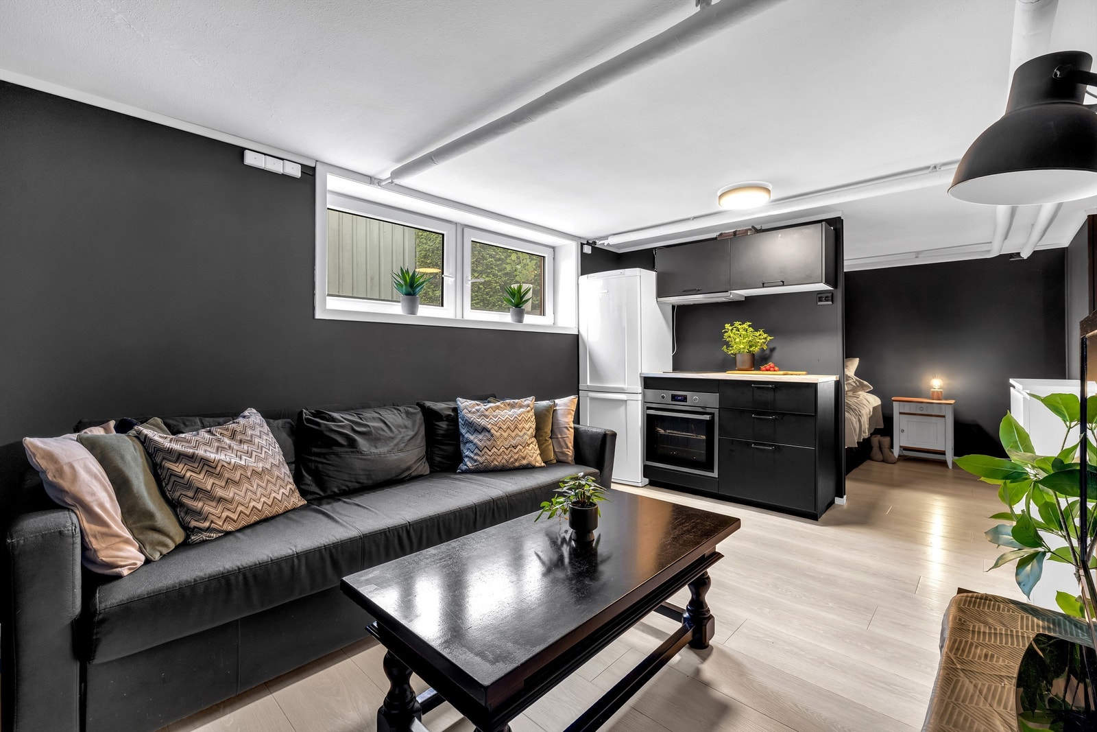 Innredet til stue med åpen kjøkkenløsning og sovealkove i kjeller. Renovert i 2019 med nytt gulv m/varmefolie . Ny smartpanel. Det elektriske ble fornyet. Ny kjøkkeninnredn. Rommet er ikke godkjent til rom for varig opphold. Galleribilde