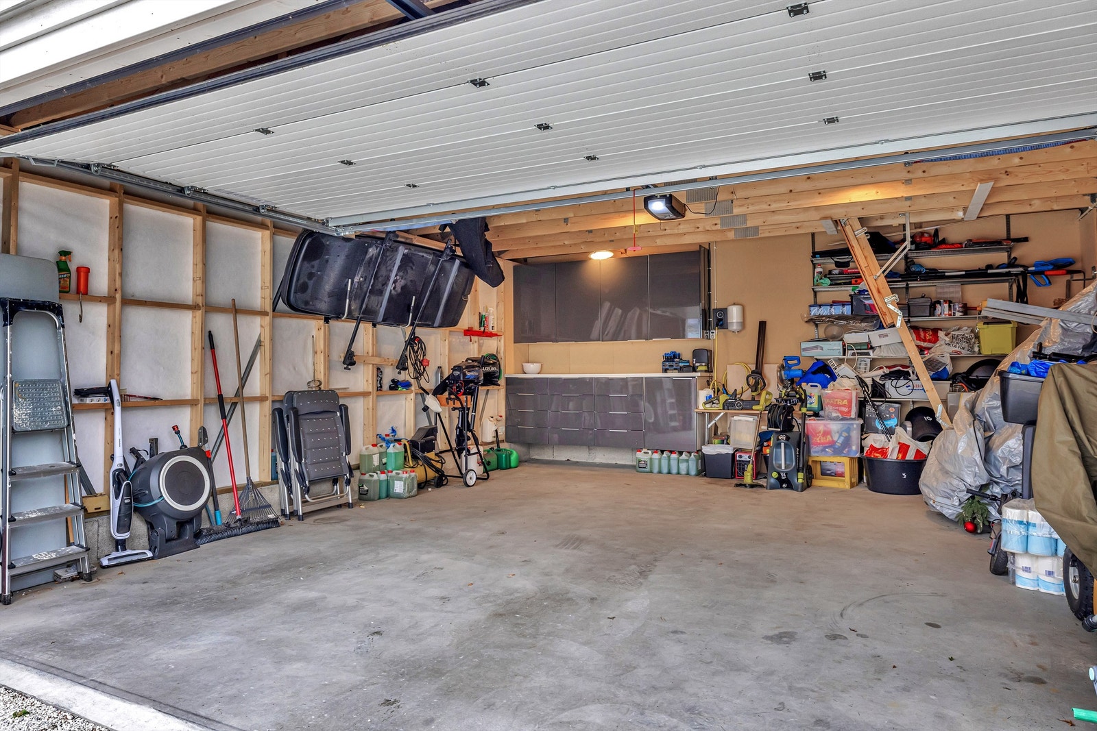 Stor garasje med midtstilt EL-bil lader, hyllesystem og Ikea innredning for praktisk arbeidsplass og oppbevaring. Eget sikringsskap i garasjen gir mulighet for flere kurser. Galleribilde