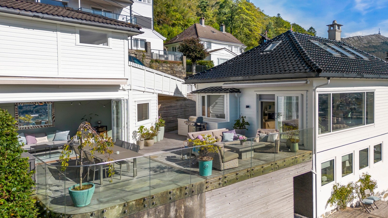 Den nydelige terrassen ligger i ly av hus og garasje. Under terrassen er det lagringsplass til diverse. Det er gjennomgang fra terrassen til nedre del av tomten hvor er hagesti, bærbusker, plen, bed, belysning m.m. Galleribilde