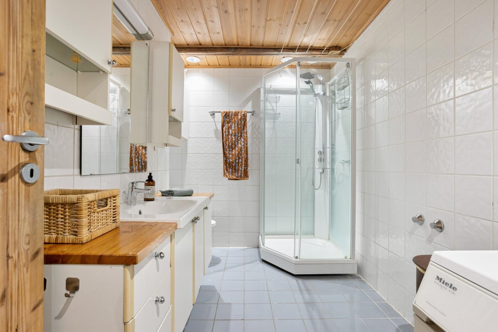 Badet har flislagt gulv med gulvvarme og flislagte vegger samt opplegg for vaskemaskin. Galleribilde