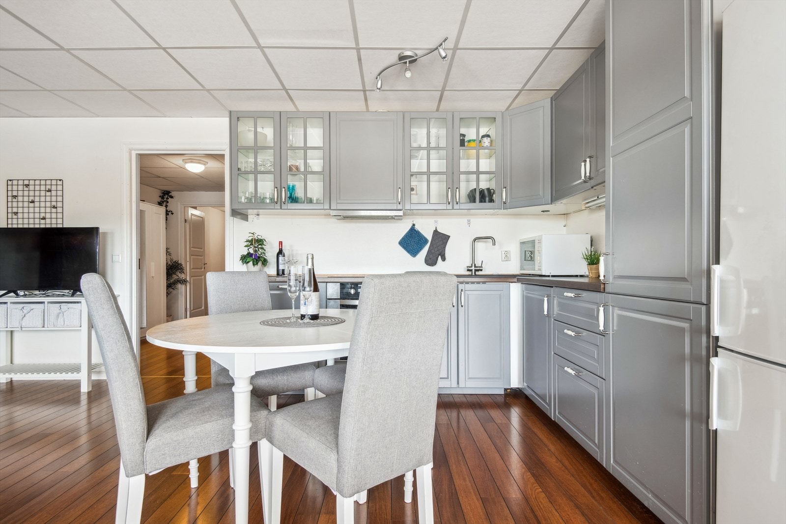 Kjøken med profilerte grå frontar og glasruter i nokre overskåp. Det er god skap- og benkeplate Galleribilde