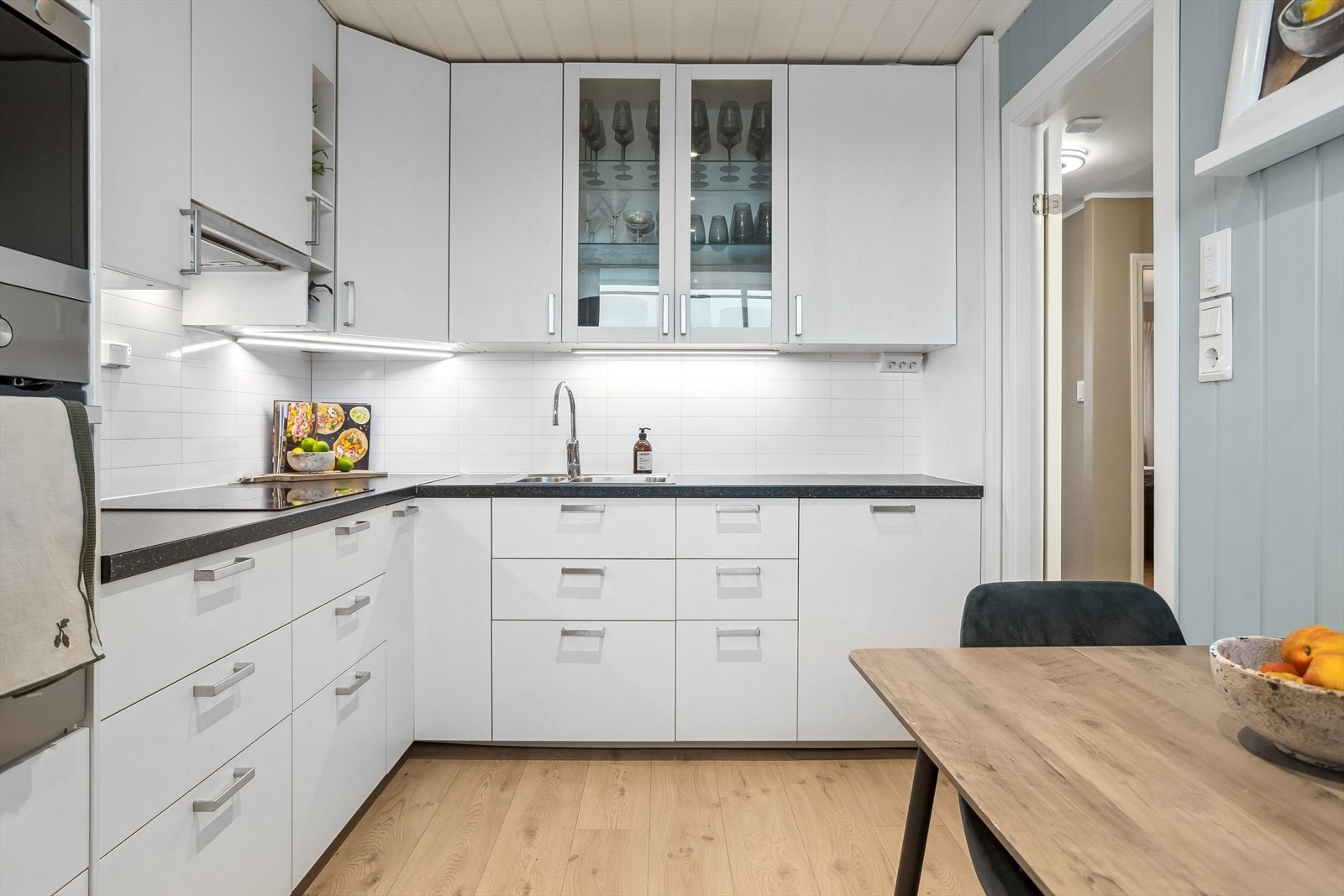Kjøkkenet er innredet med et tidløst design med hvite slette fronter, laminat benkeplate og nedfelt stålvask. Galleribilde