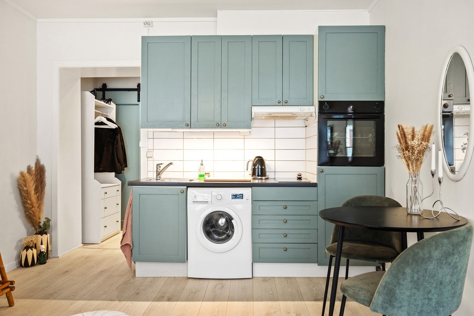 Flott kjøkken med god skap- og benkeplass, utstyrt med grønne, profilerte fronter, laminatbenkeplate og en nedfelt oppvaskkum i rustfritt stål med ettgreps svingbart blandebatteri. Galleribilde