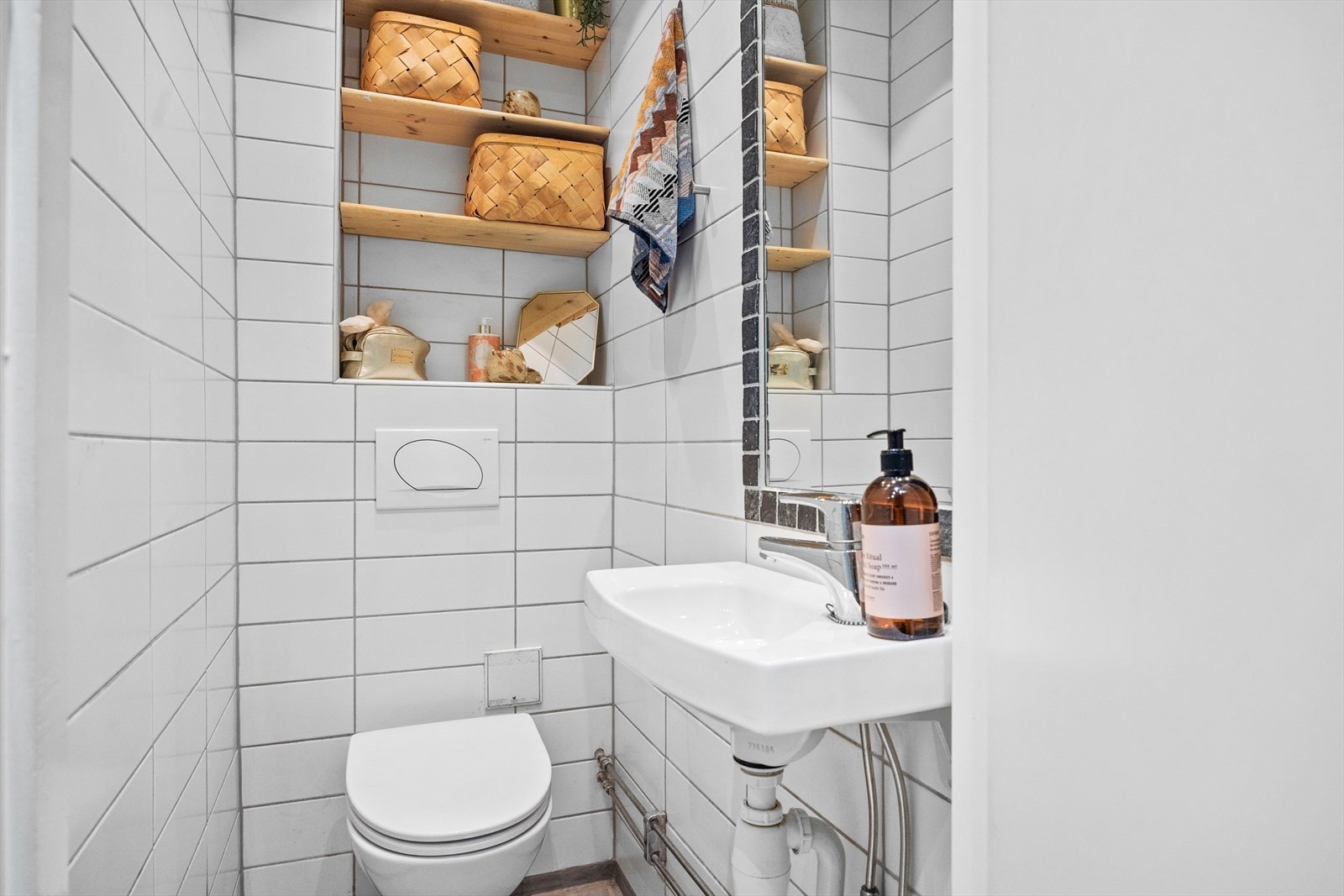 Pent WC-rom med flislagte vegger og mikrosement på gulv. Rommet har gulvvarme og nedsenket tak med downlights. Galleribilde