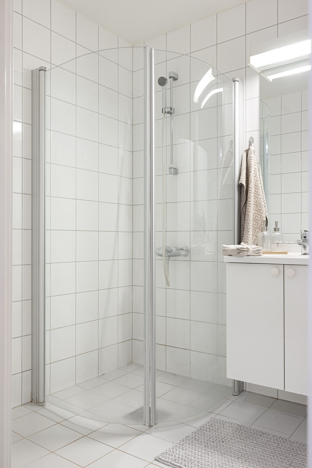 Badet er utstyrt med et servantskap med nedfelt servant, et speil med lys over, et vegghengt klosett med innebygd sisterne, samt en dusjsone med innfelte dusjdører i herdet glass. Galleribilde