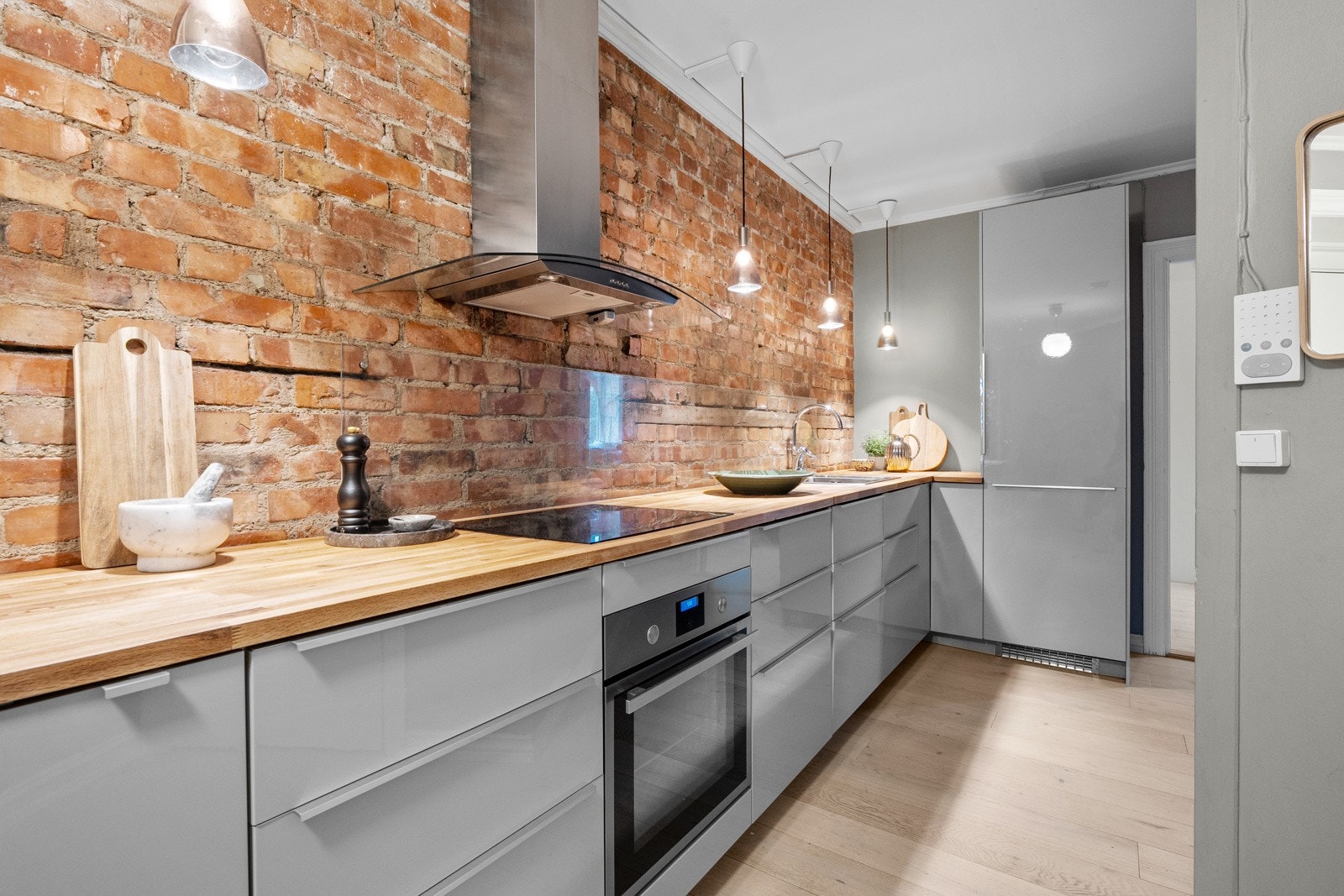 Innredningen har grå høyglansfronter og gyllen, solid heltrebenkeplate med nedfelt kum i stål. Galleribilde