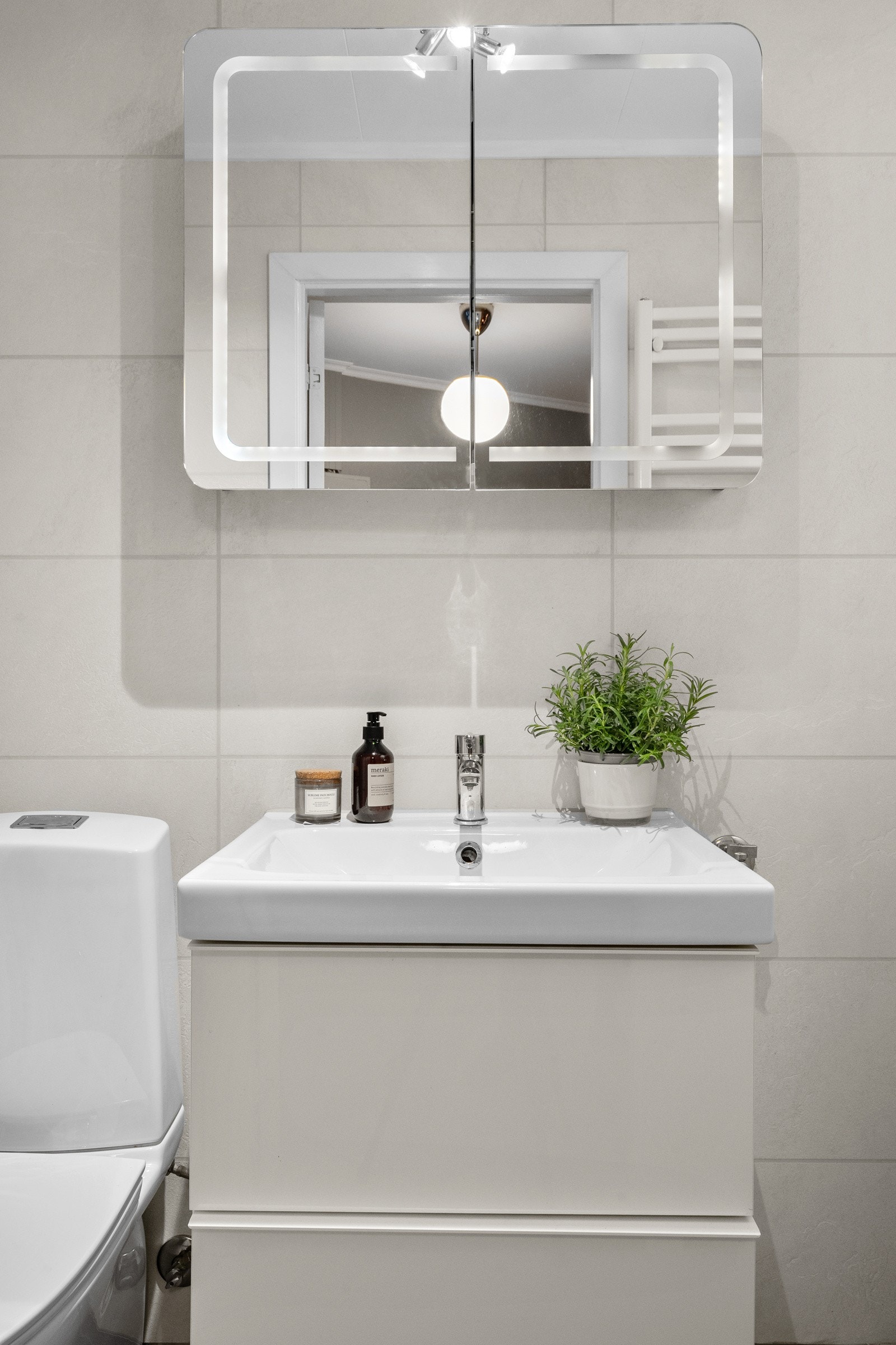 Badet har en heldekkende servant på en skuffeseksjon og et dobbelt speilskap med integrert belysning. Galleribilde