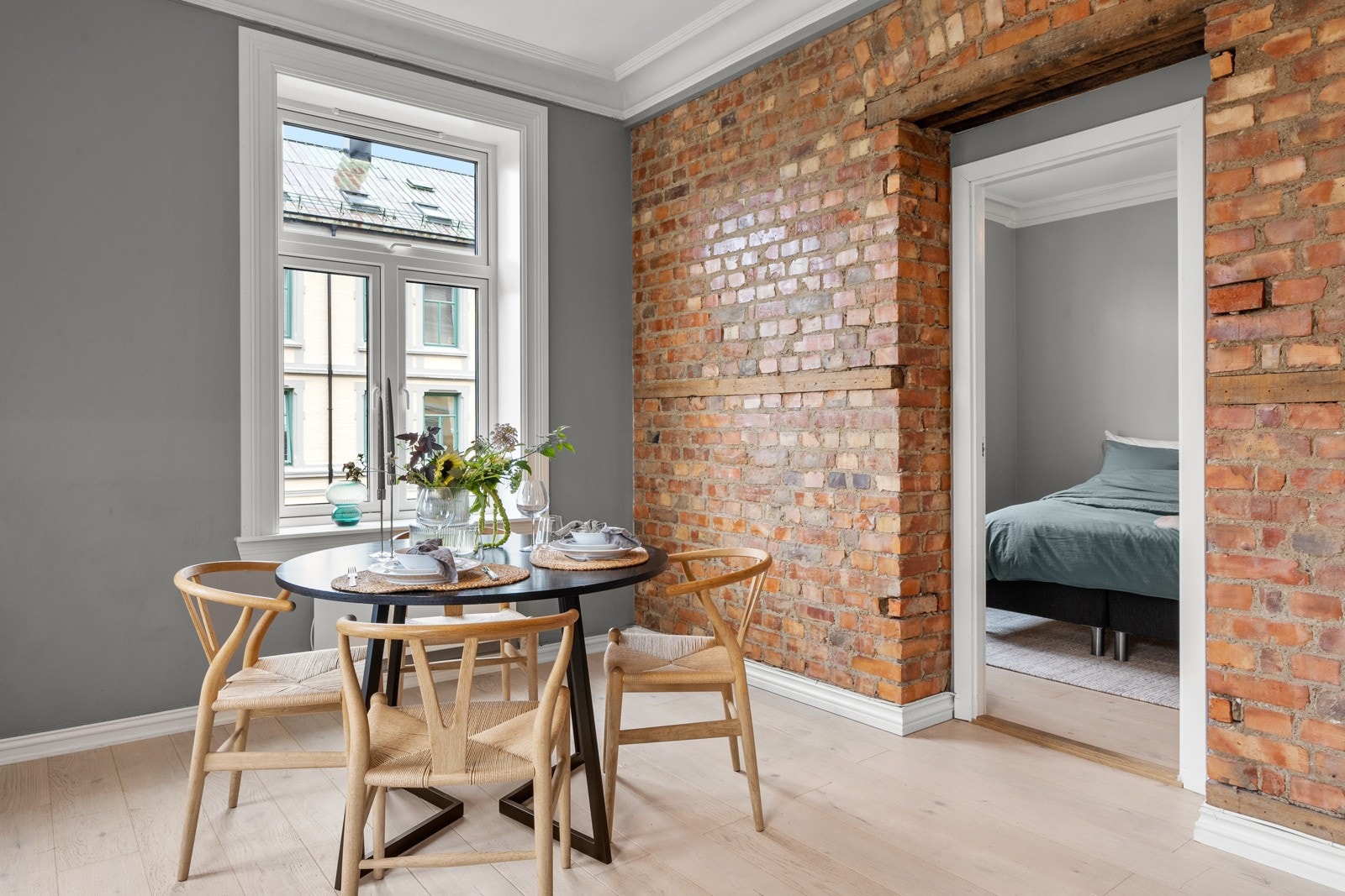 De gråmalte veggene fremhever det lyse gulvet, og en hel vegg i original teglstein gir rommet særpreg. Galleribilde