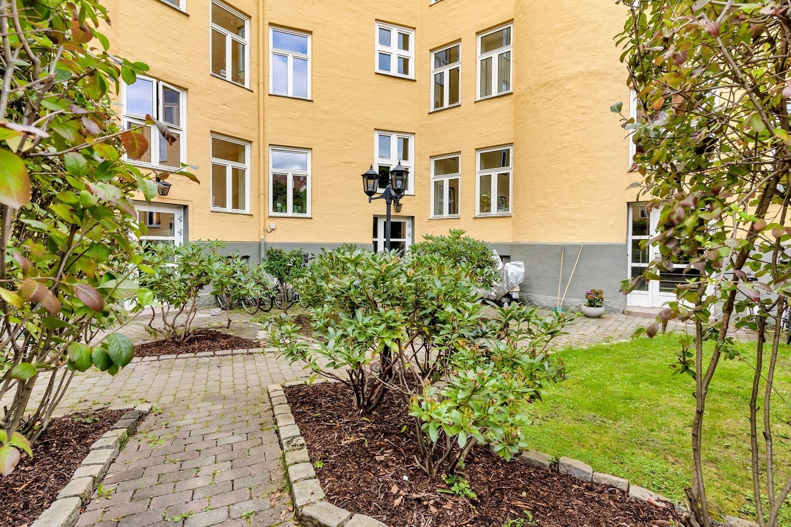 Fellestomten er pent opparbeidet, og i en lun og skjermet bakgård er det frodig beplantning, plenarealer, steinbelagte stier og stemningsfull utebelysning. Galleribilde