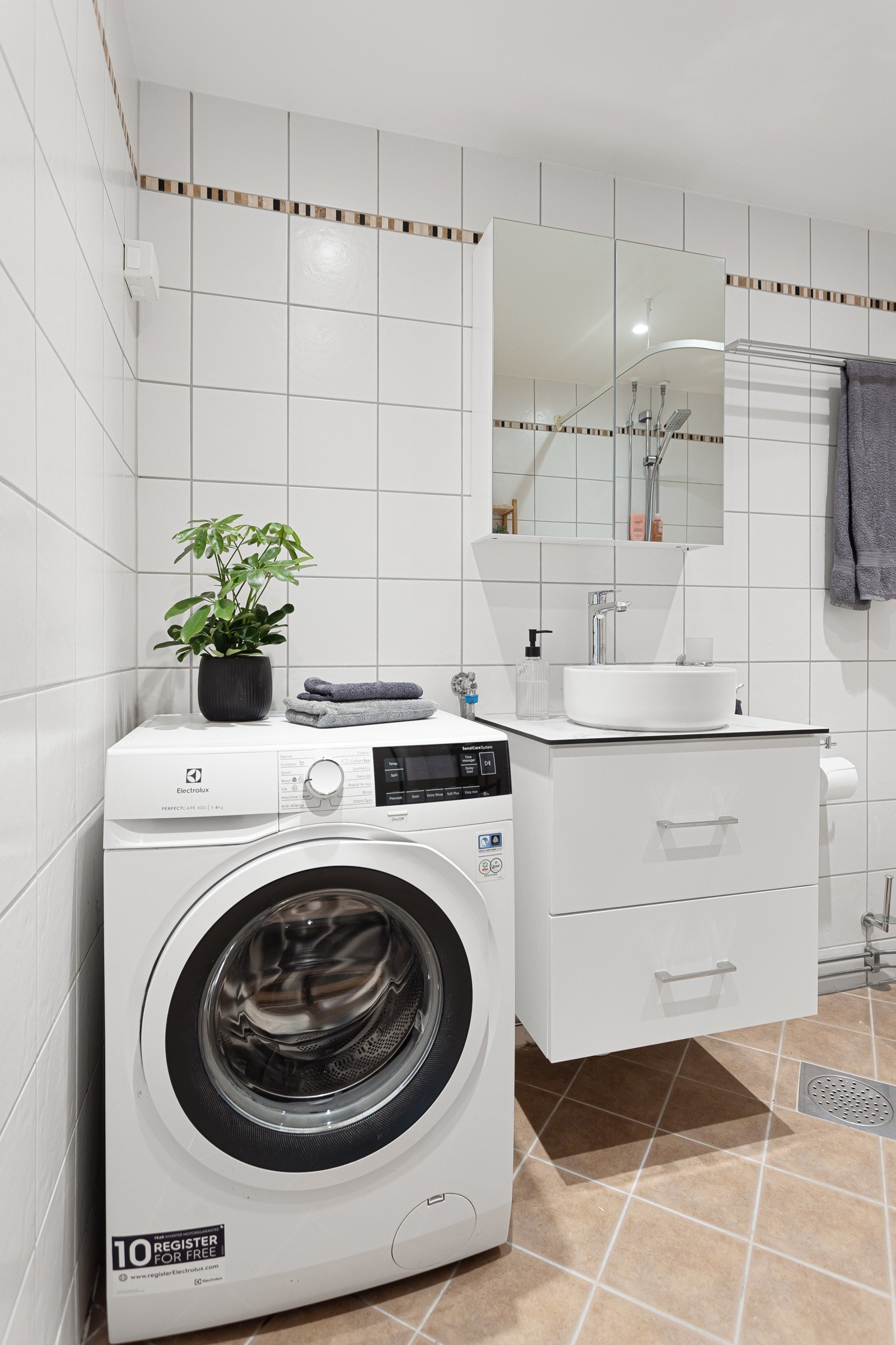 Moderne baderomsinnredning fra 2024 med skuffer og benkeplate med ovenpåliggende servant, vegghengt speilskap over. Galleribilde